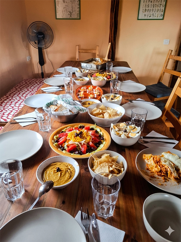 Mesa de madera larga con platos de comida saludable y variada, como ensalada, hummus y pasta, para compartir en un retiro de crecimiento personal